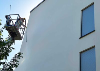 Professionelle Fassadenwäsche am Mehrfamilienhaus auf mobiler Hebebühne
