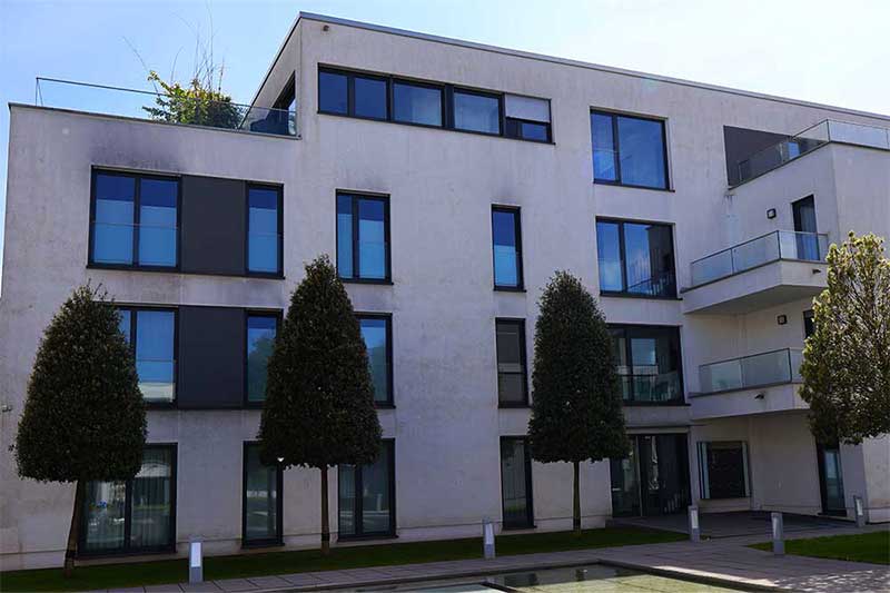 Verschmutzte Mehrfamilienhausfassade vor der algenfiX Fassadenreinigung