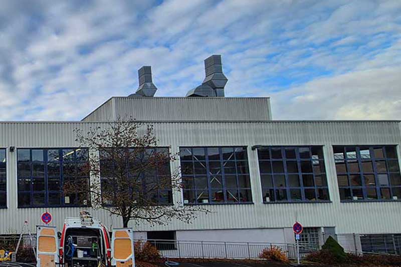 Von Mikroorganismen befallene Industriegebäudefassade vor algenfiX Fassadenwäsche